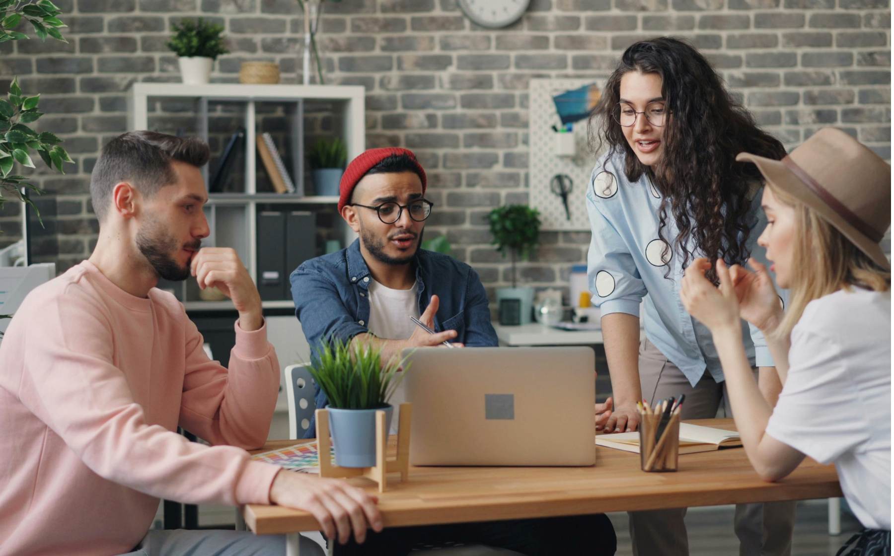 A small team gathers around a laptop, discussing ideas together